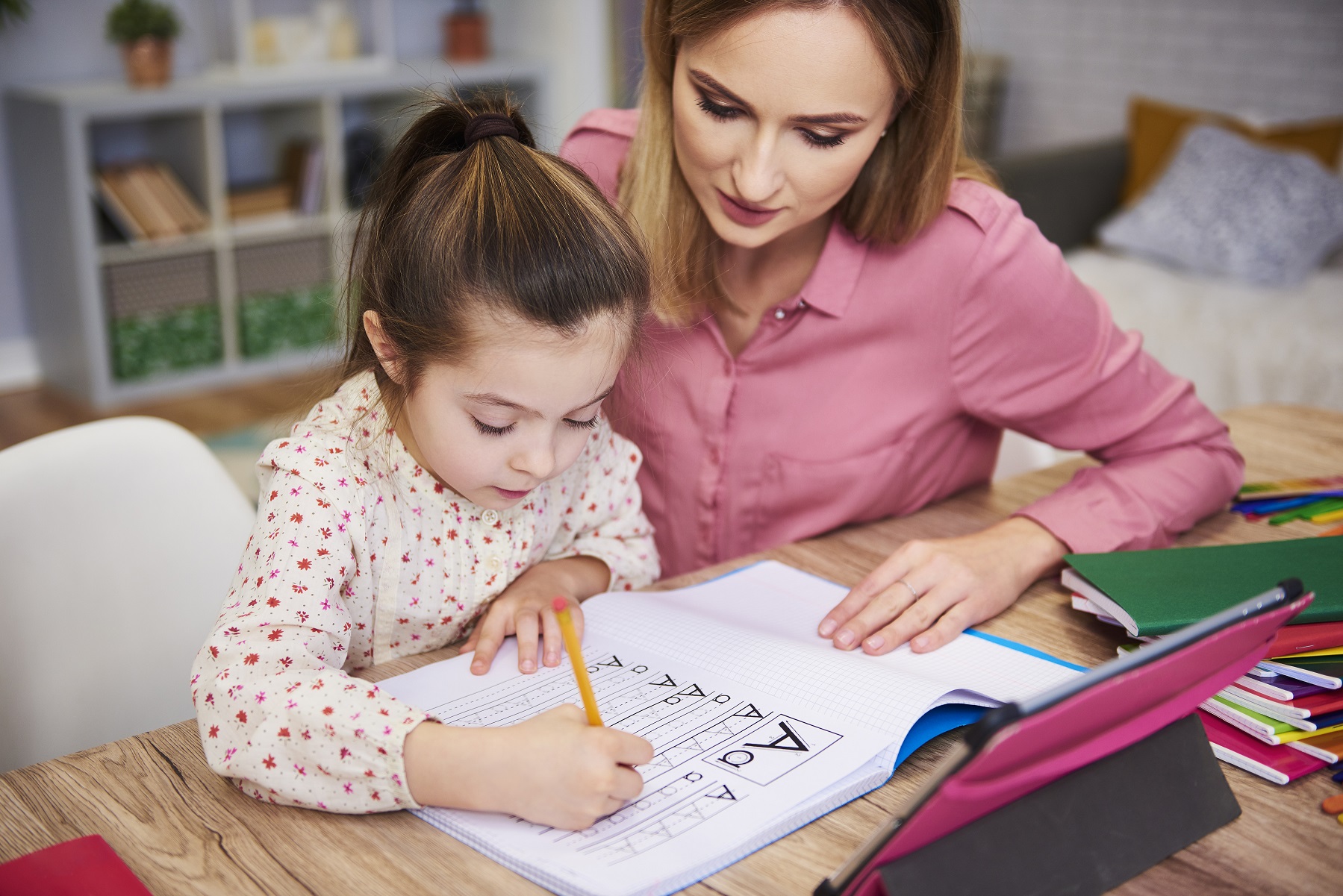 Young woman helping a girl with homework.